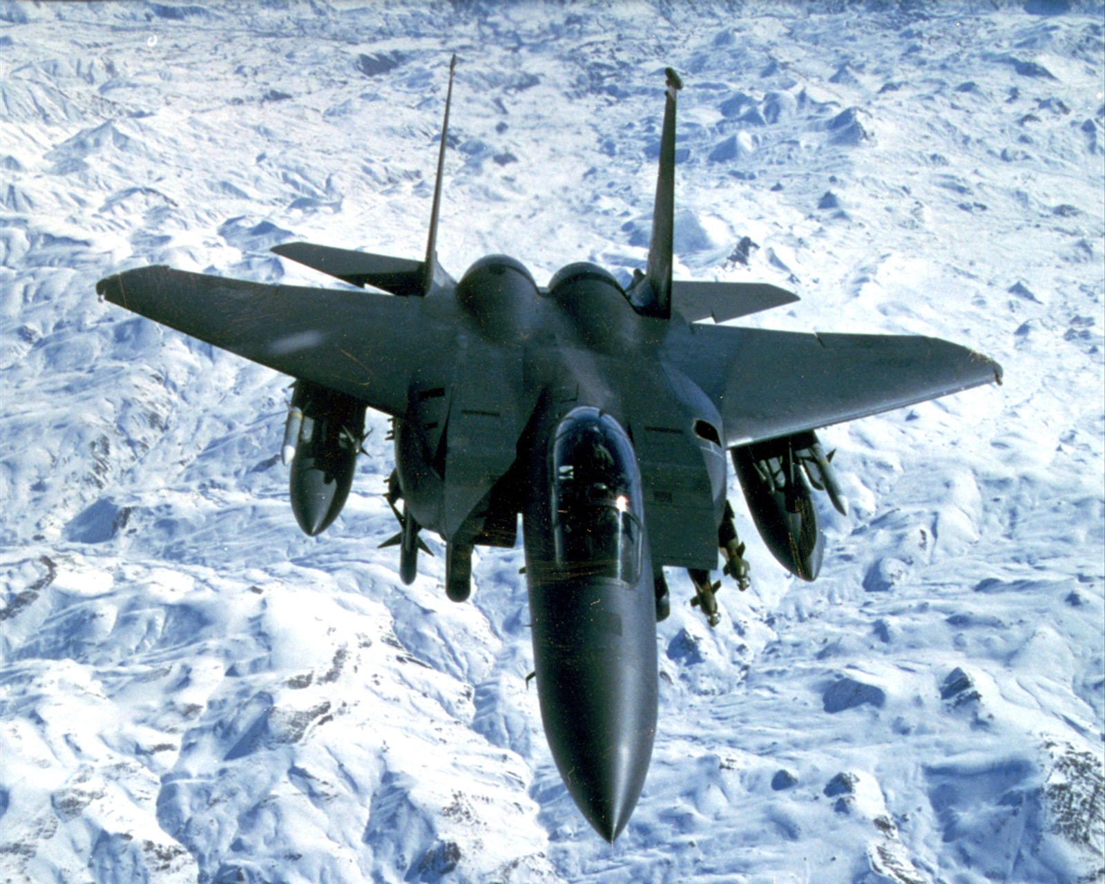 Fighter jet flying over snow-covered mountains